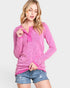 Woman wearing a pink long-sleeve top with a V-neck and button details on a white background