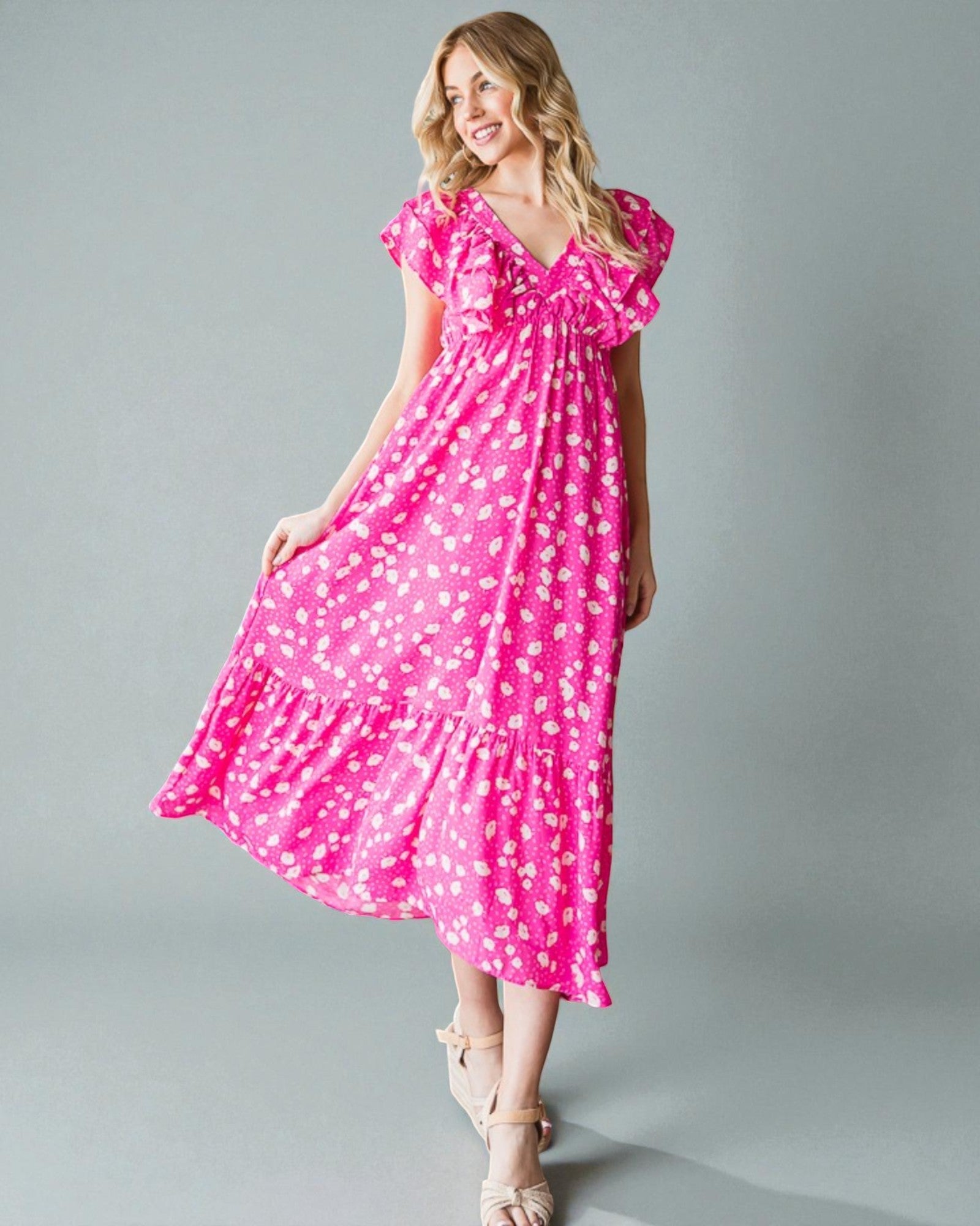 Woman wearing a pink dress with white polka dots on a gray background