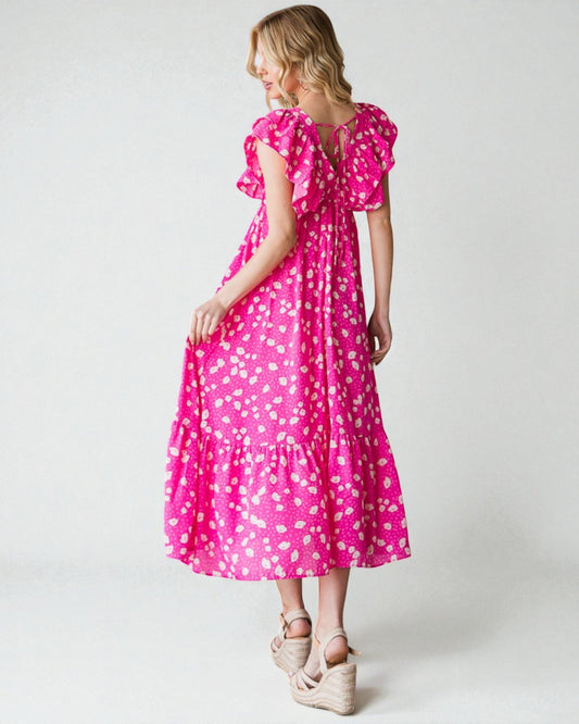 Woman wearing a pink dress with white floral pattern on a plain background