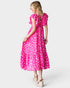 Woman wearing a pink dress with white polka dots on a white background