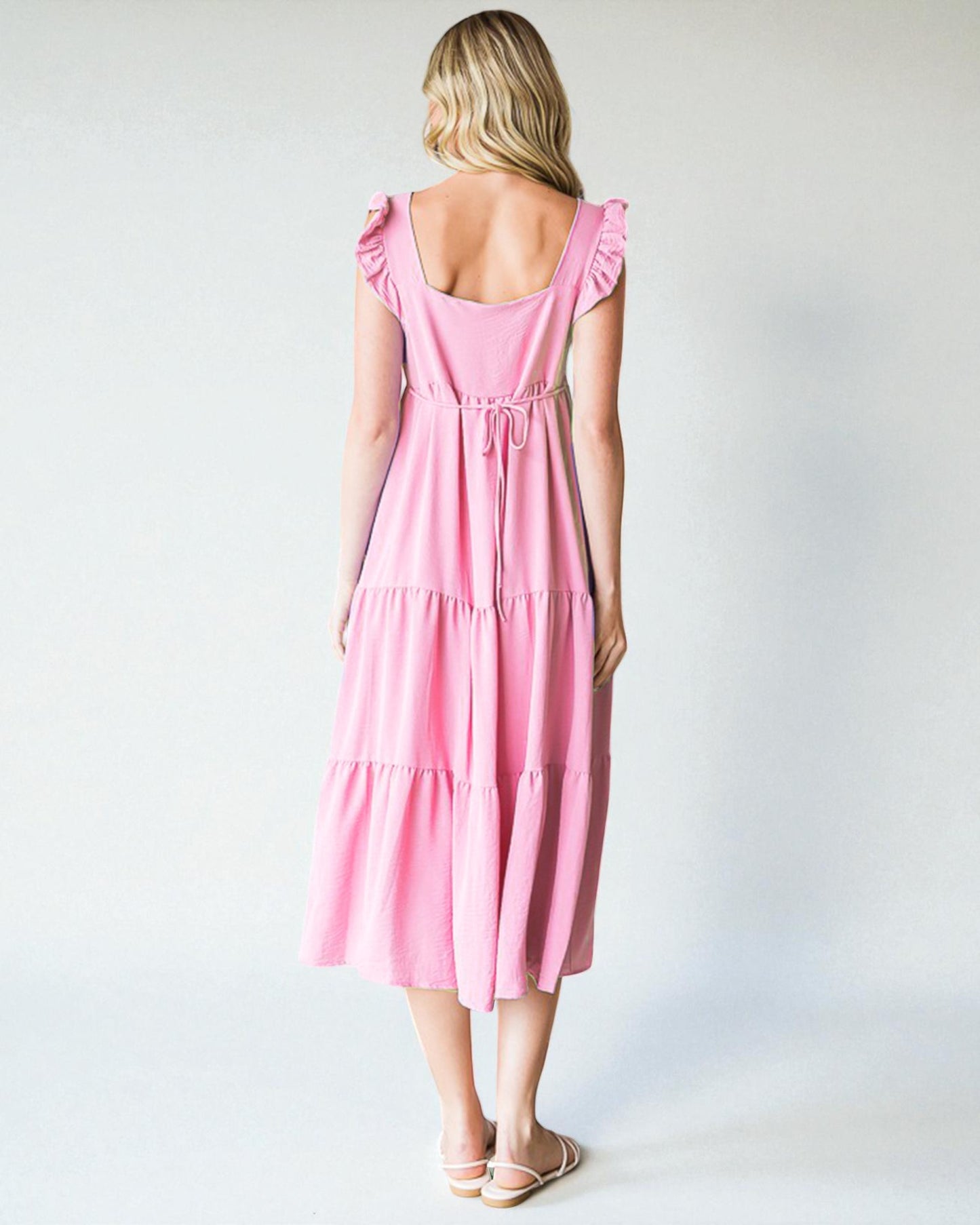 Woman wearing a pink dress with ruffled sleeves on a white background