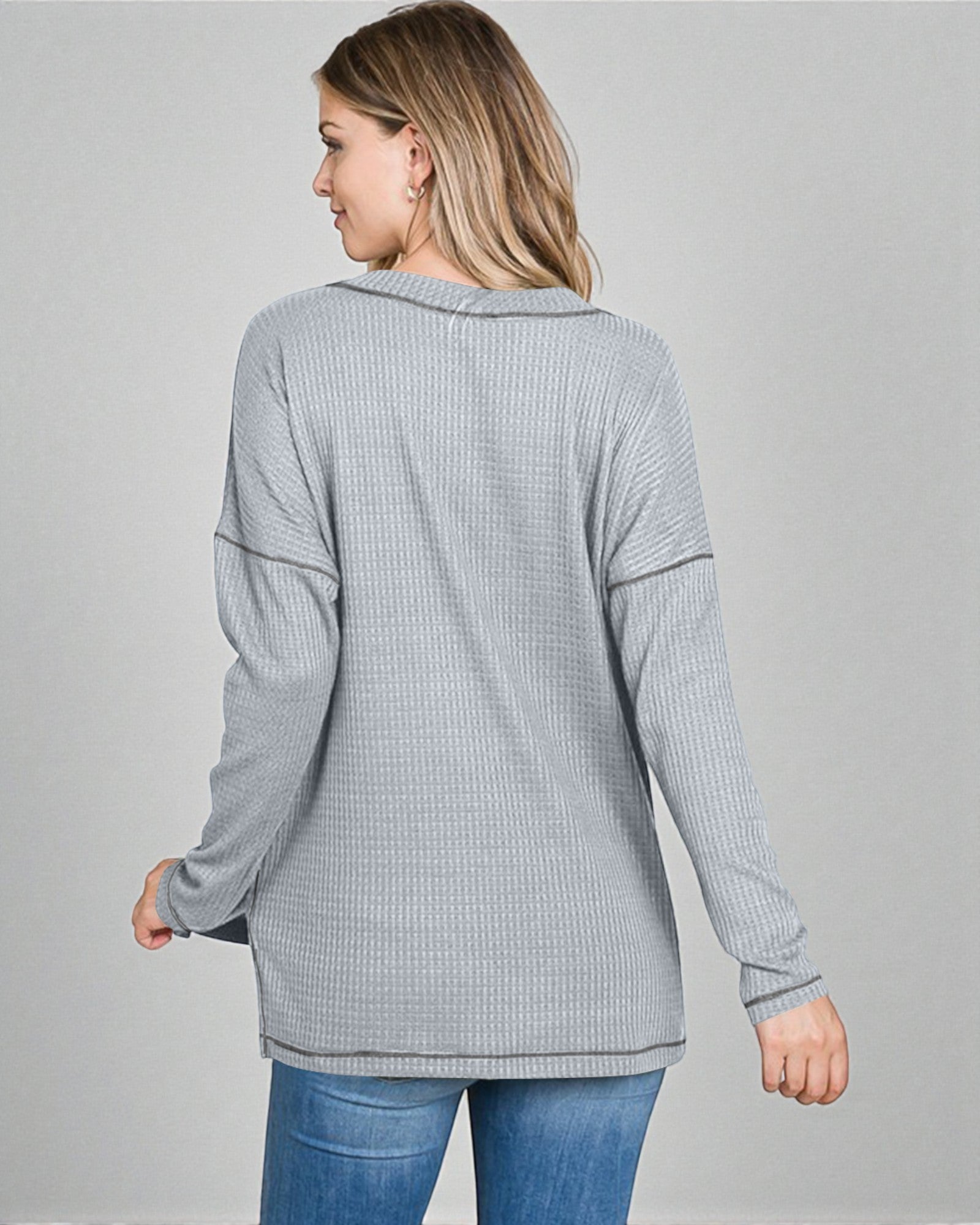 Woman wearing a gray ribbed long-sleeve top on a gray background