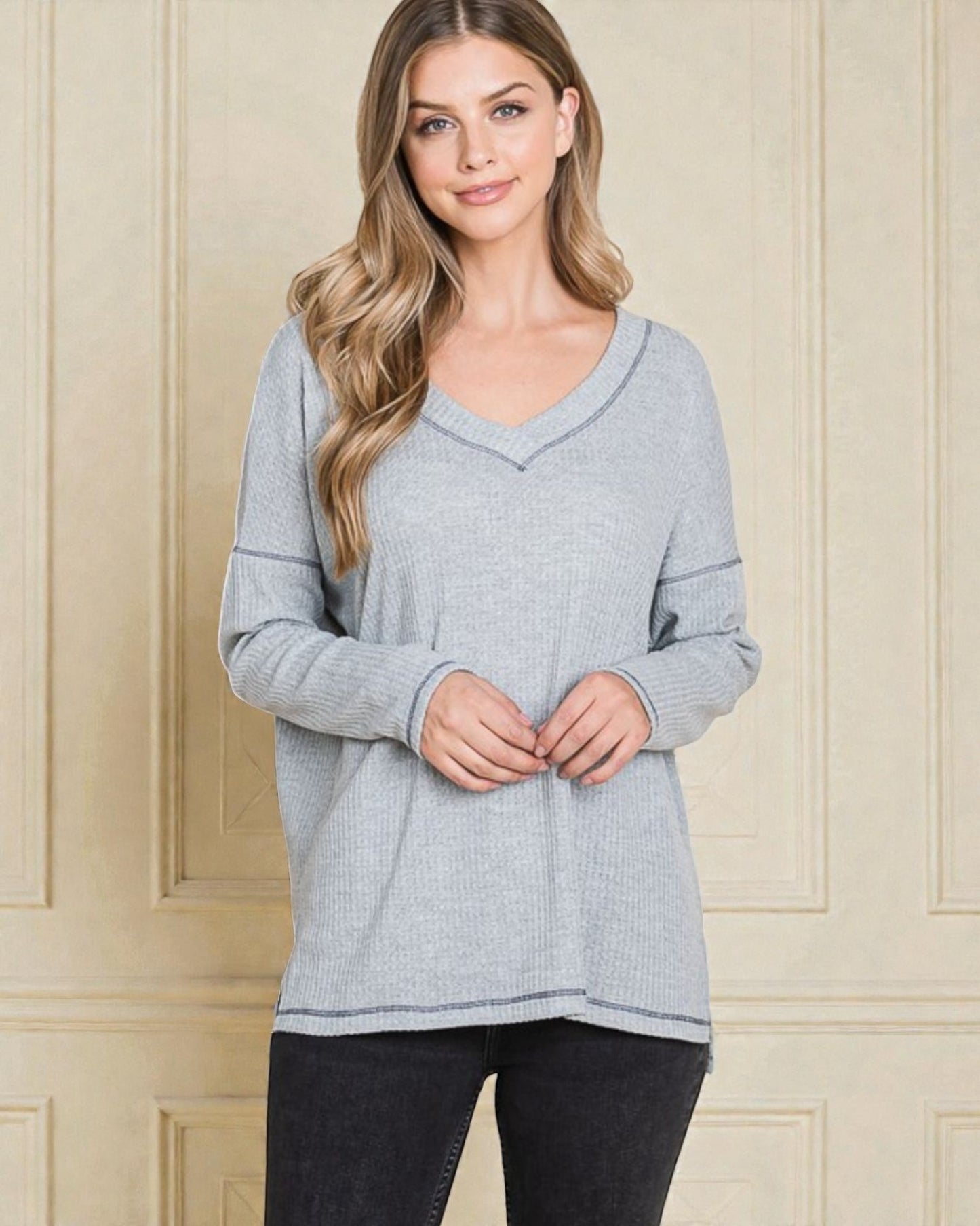 Woman wearing a gray sweater against a beige wall