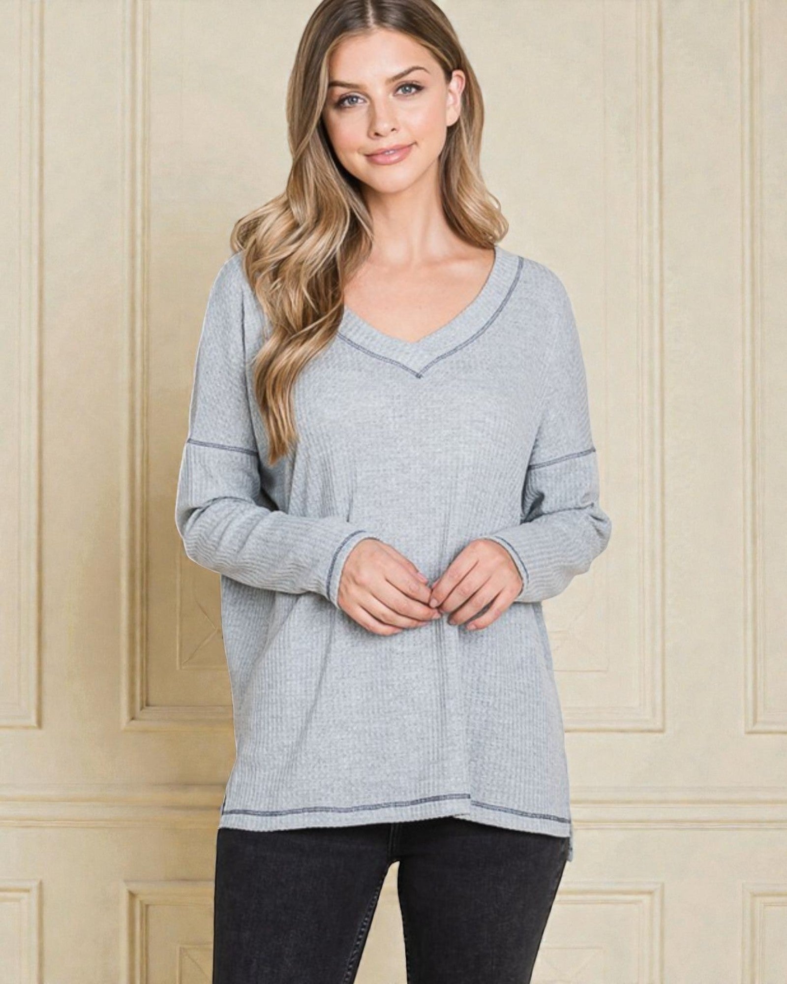 Woman wearing a gray sweater against a beige wall