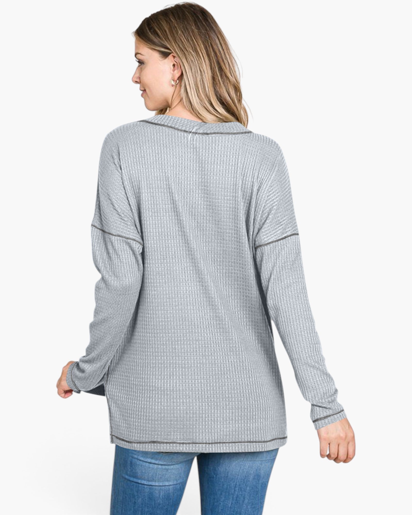 A woman shown from the back wearing a light gray waffle-knit long-sleeve top and blue jeans against a plain white background.