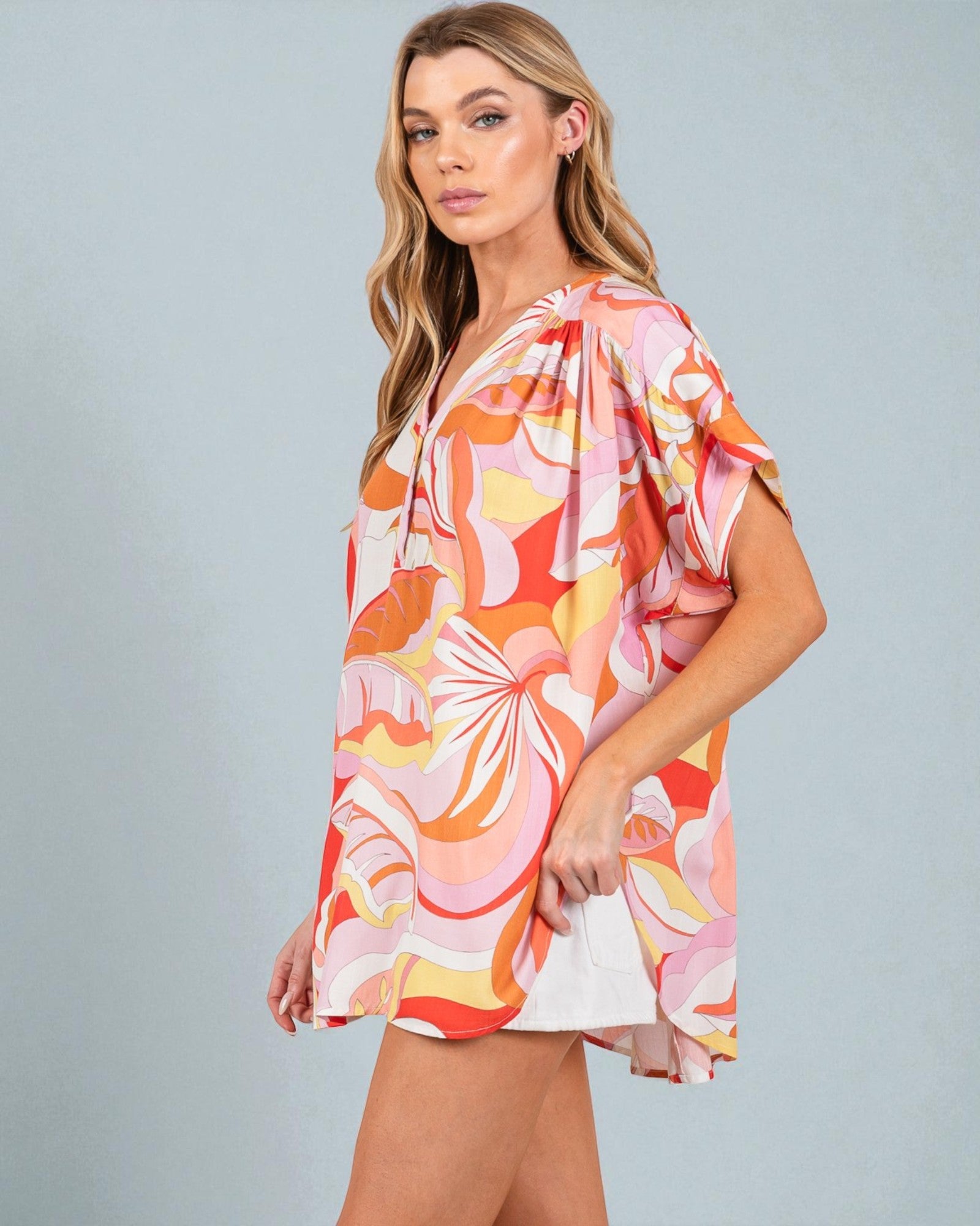 Woman wearing a colorful floral dress against a gray background