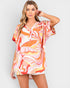 Woman wearing a colorful tropical print dress on a plain background