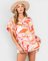 Woman wearing a colorful patterned cover-up dress and beige hat on a white background