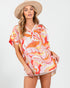 Woman wearing a colorful floral dress and beige hat on a white background