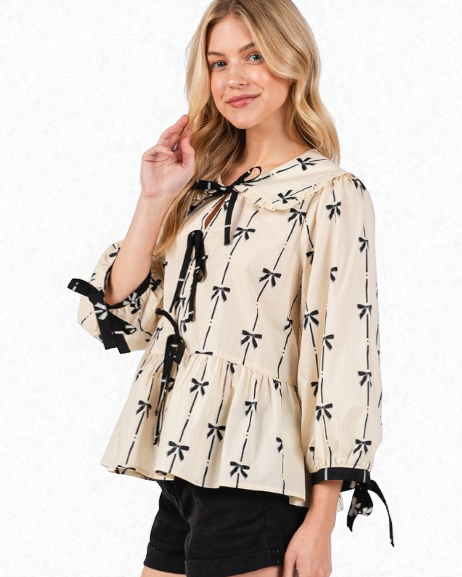 Woman wearing a beige blouse with black bow patterns on a white background