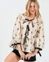 Woman wearing a beige blouse with black bow patterns on a white background