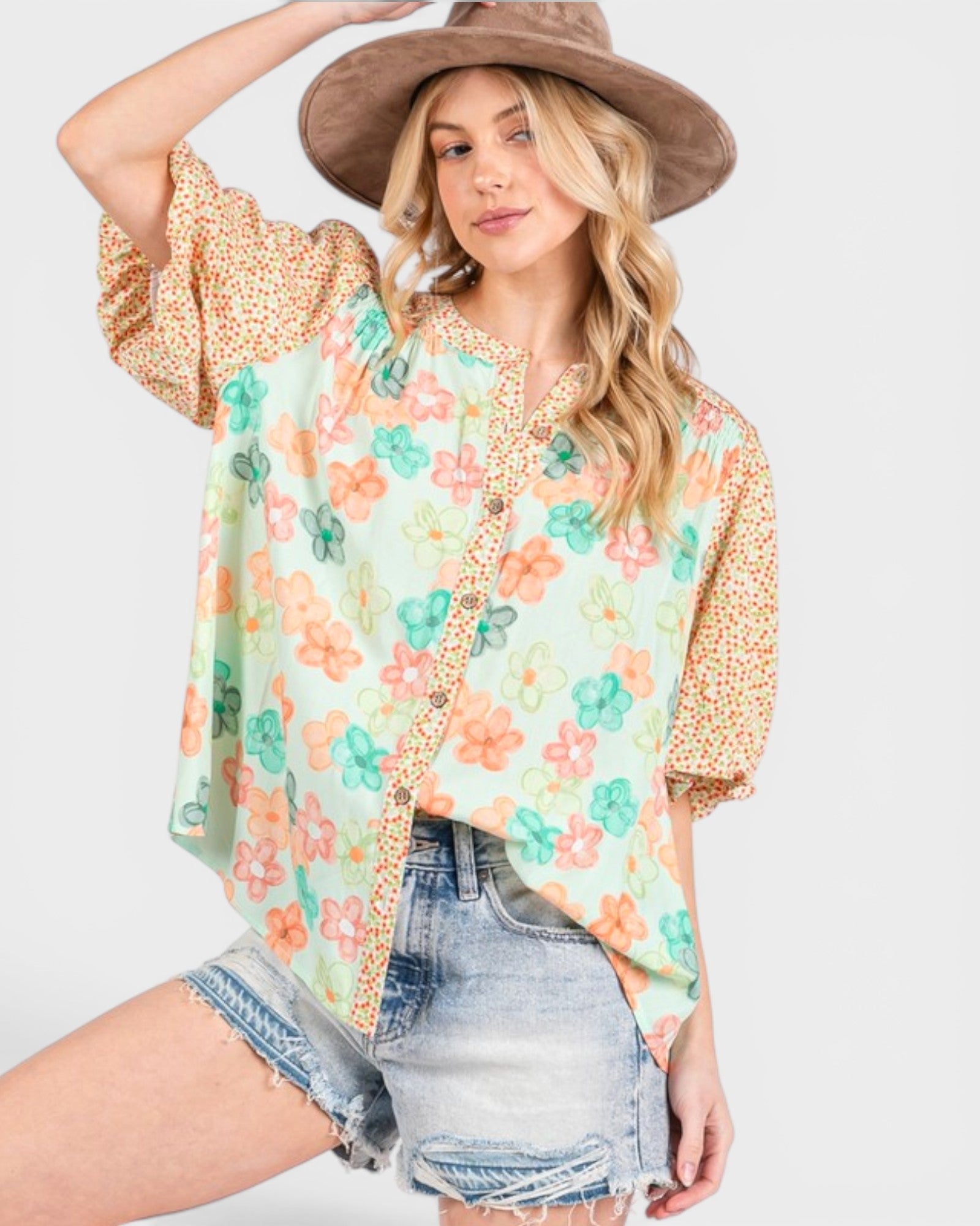 Woman wearing a floral blouse with denim shorts on a white background
