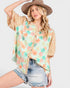 Woman wearing a floral blouse with denim shorts on a white background