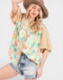 Woman wearing a floral kimono-style top with a plain background