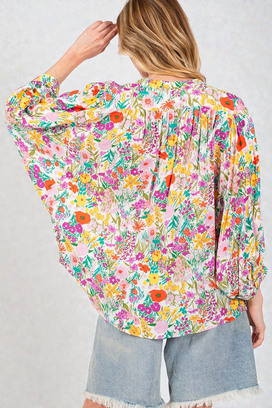 Woman wearing a colorful floral blouse with a plain background