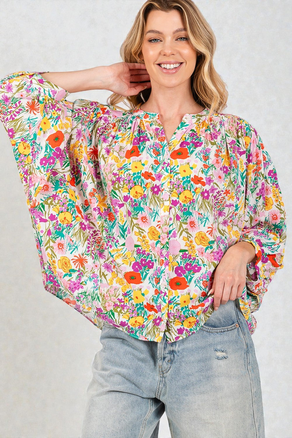 Woman wearing a colorful floral blouse with a plain background