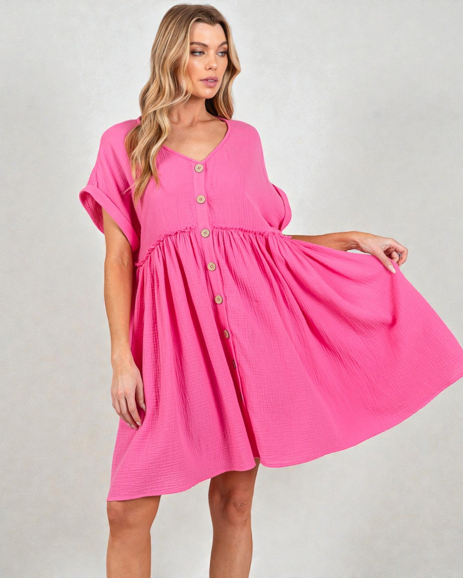 Woman wearing a pink dress with button details on a plain background