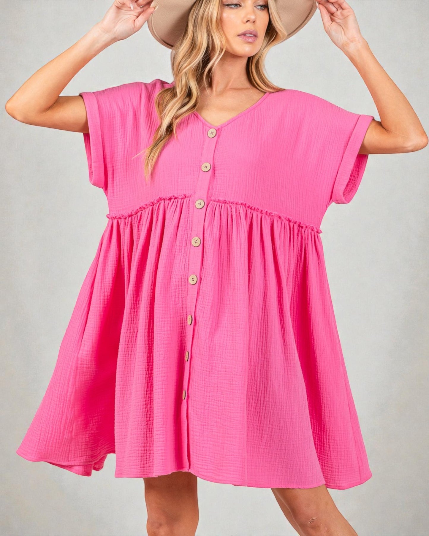 Woman wearing a pink dress with button details on a plain background