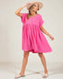Woman wearing a pink dress and beige hat on a plain background