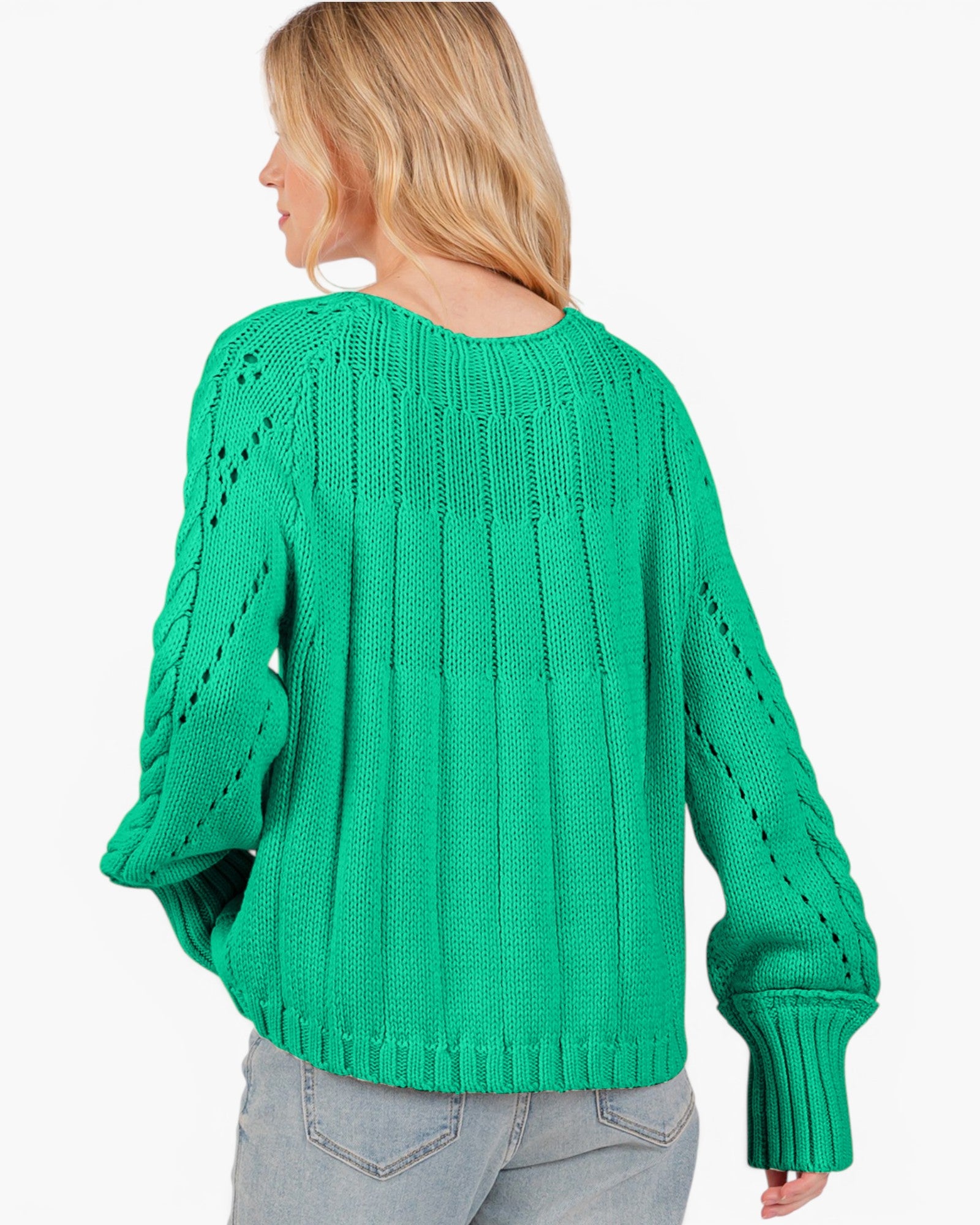A woman shown from the back wearing a bright green cable-knit sweater and light gray jeans against a plain white background.
