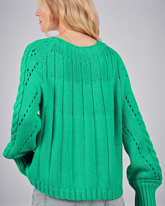 Green knitted sweater worn by a person on a gray background