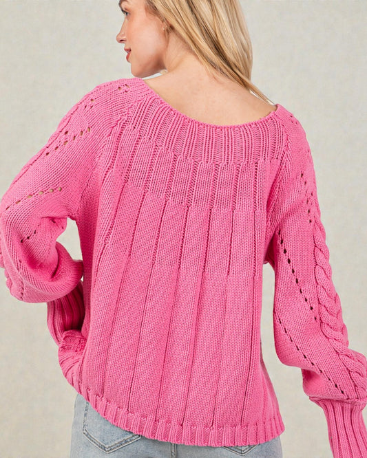 Person wearing a pink knitted sweater against a neutral background
