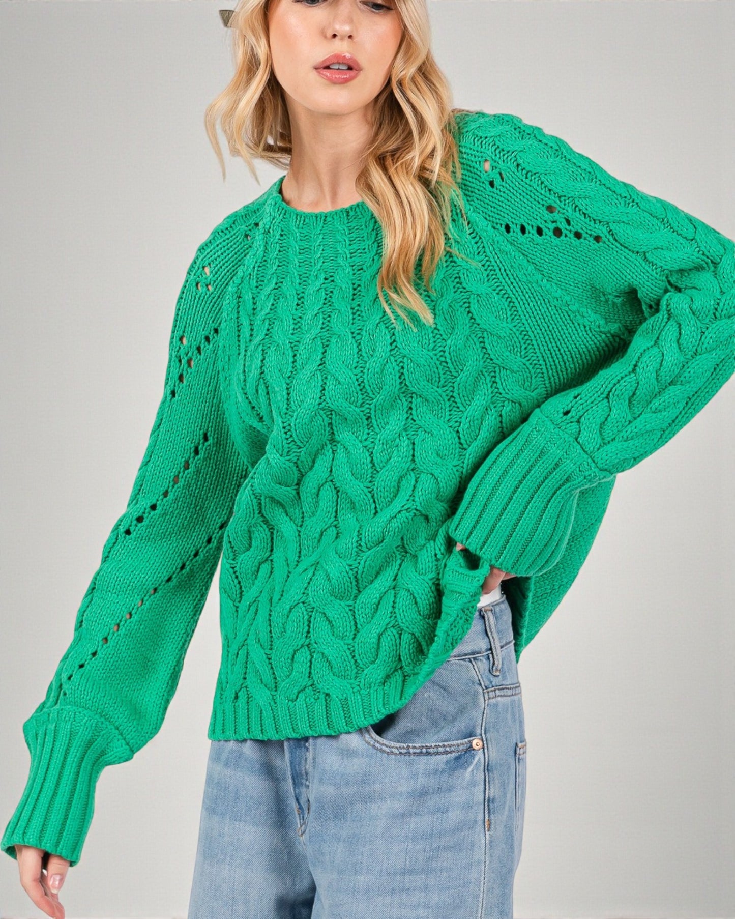 Person wearing a green knitted sweater with a gray background