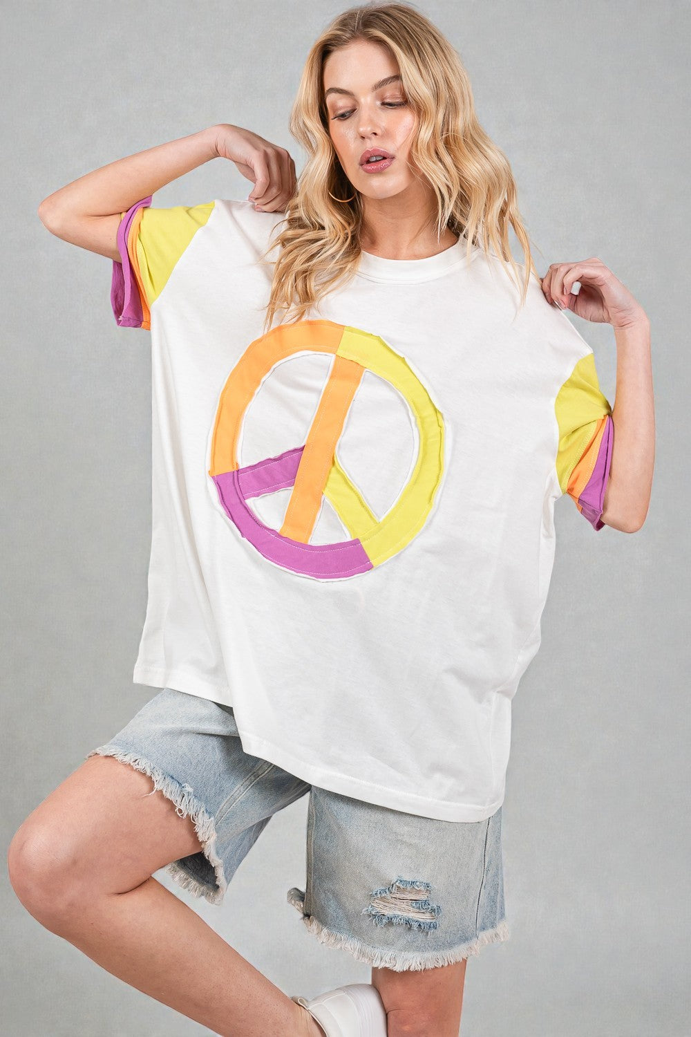 Woman wearing a white t-shirt with a colorful peace symbol design on a gray background