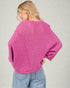 Woman wearing a pink knitted sweater and blue jeans on a plain background