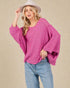 Woman wearing a pink sweater and light blue jeans against a beige background