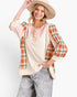 A woman modeling a bohemian-style patchwork top with cream panels, peach sleeves, and orange plaid side panels, paired with gray jeans and a beige wide-brim hat against a white studio background.