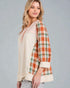 Woman wearing a plaid shirt over a beige top on a gray background