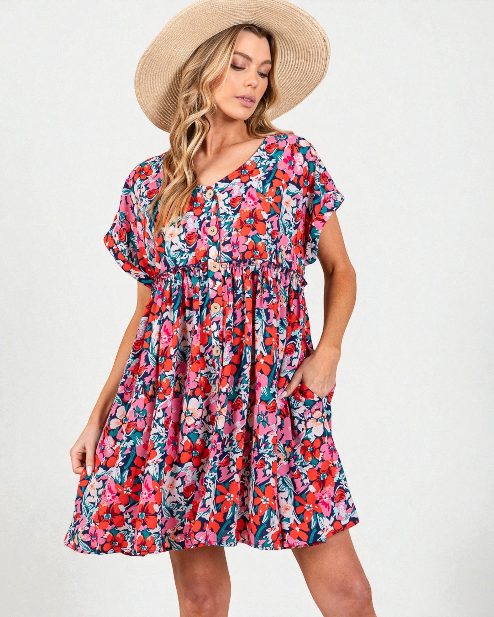 Woman wearing a colorful floral dress and straw hat on a white background