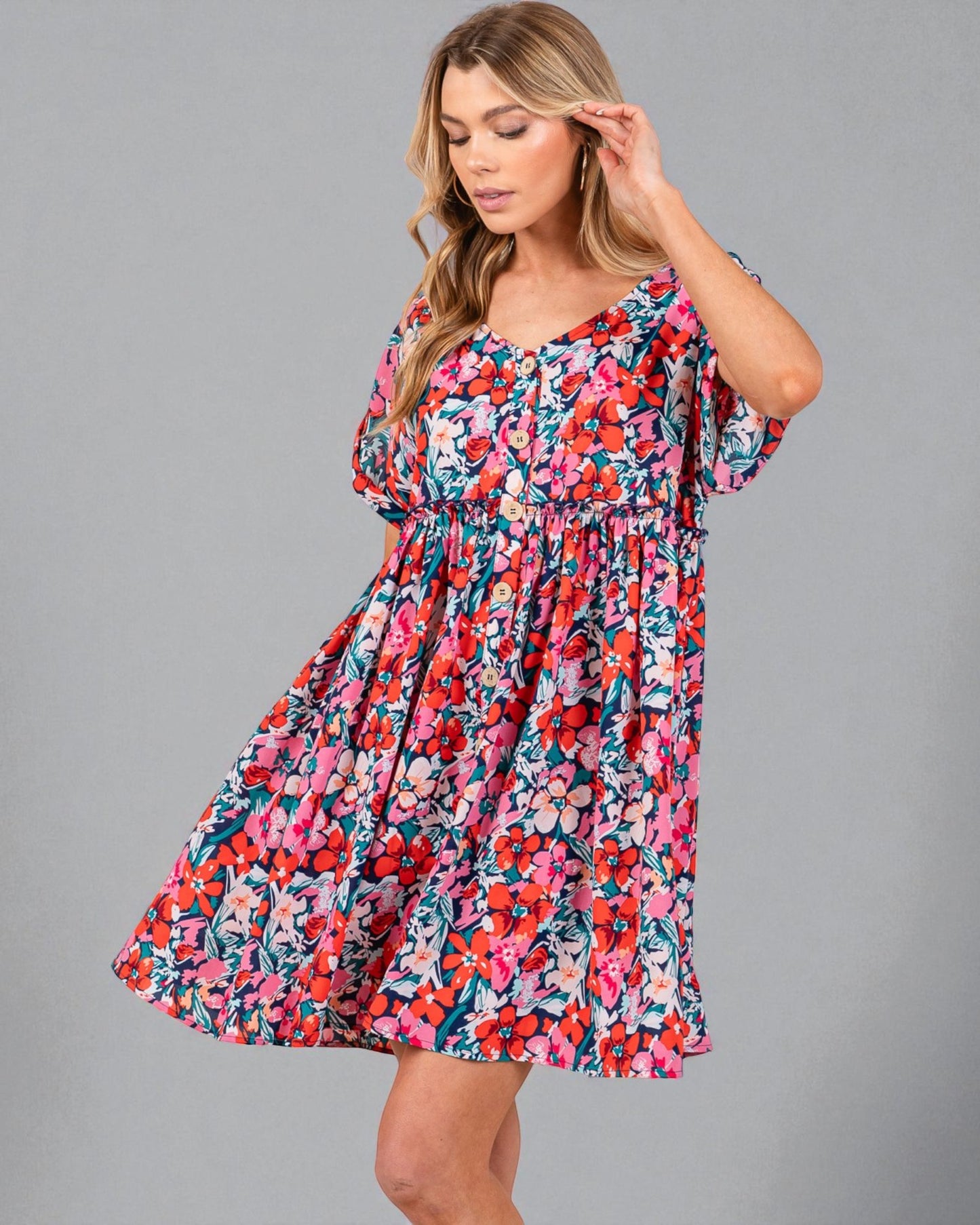 Woman wearing a colorful floral dress on a gray background