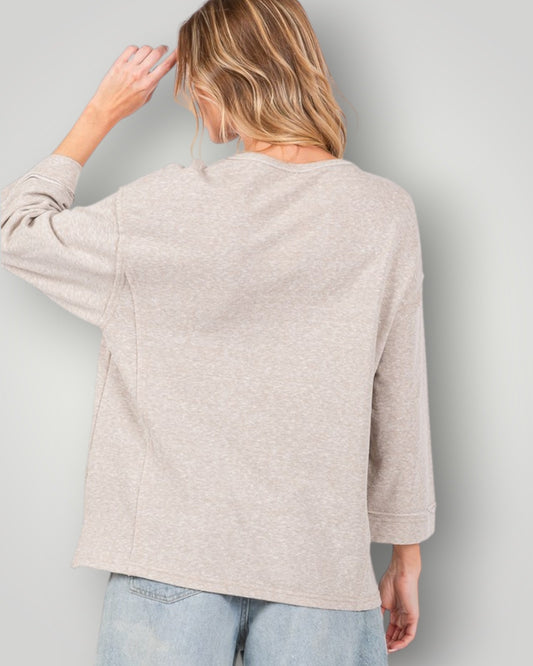 Woman wearing a beige sweater against a plain background