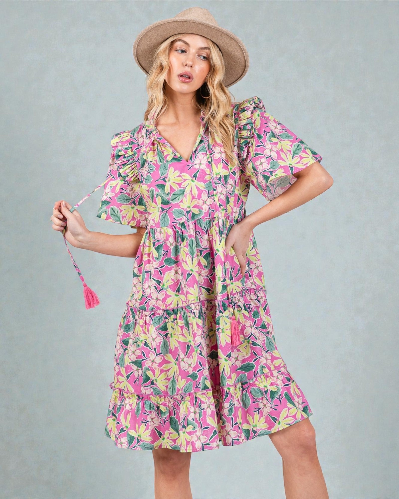Woman wearing a colorful floral dress and hat against a gray background