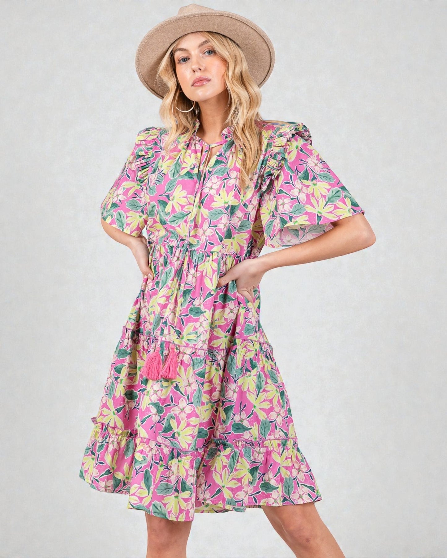 Woman wearing a colorful floral dress and hat on a plain background