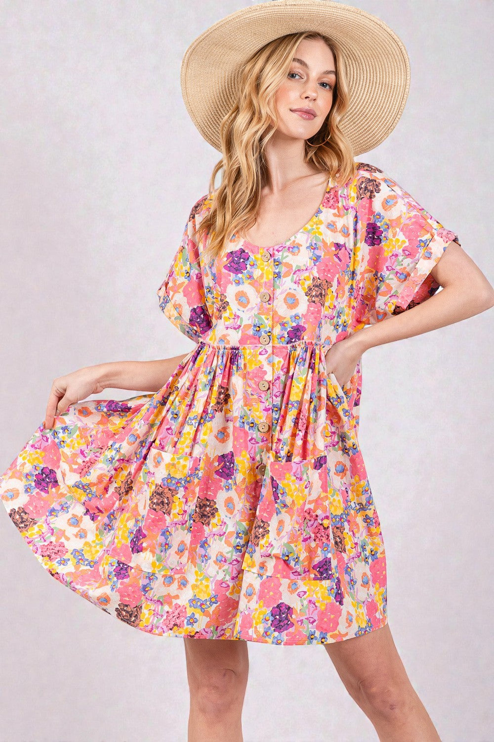 Woman wearing a colorful floral dress and straw hat on a light gray background