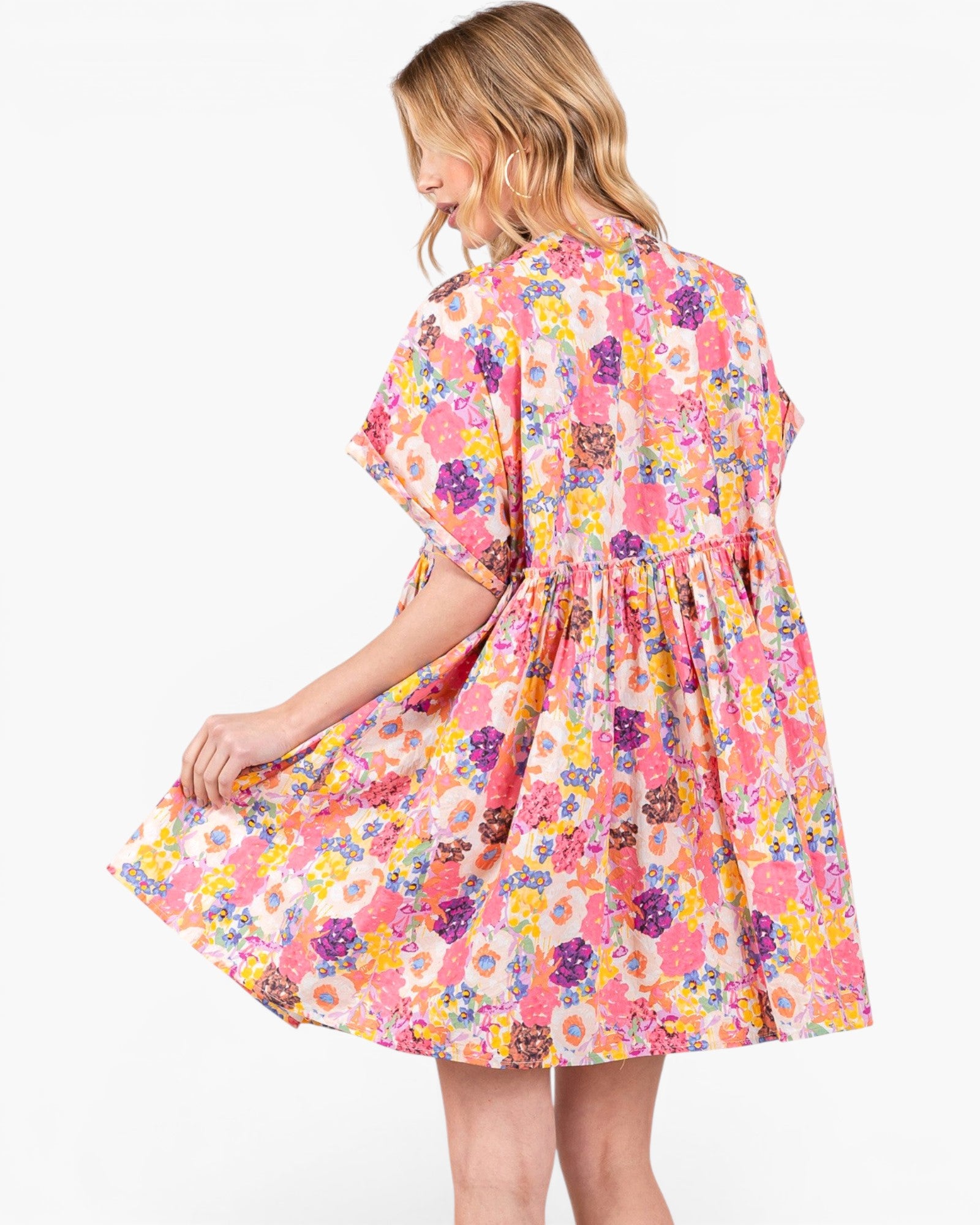 A woman wearing a short-sleeve pink floral dress, shown from the back and side against a plain white background.