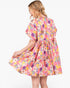 A woman wearing a short-sleeve pink floral dress, shown from the back and side against a plain white background.