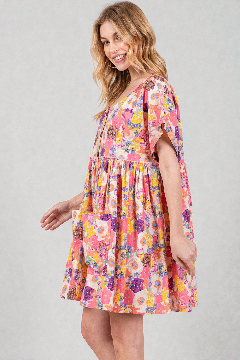 Woman wearing a colorful floral dress on a plain background