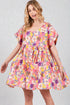 Woman wearing a colorful floral dress on a plain background