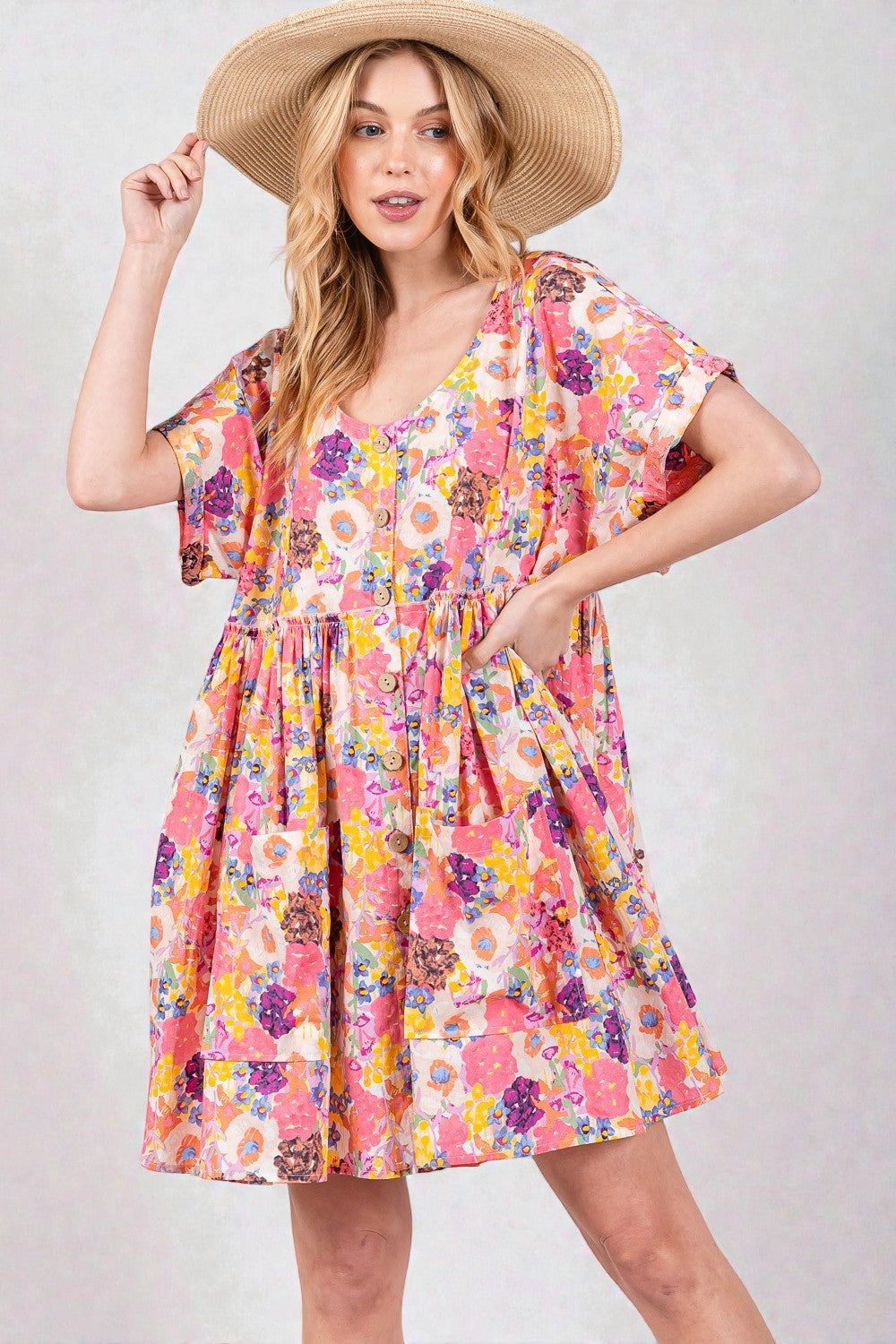 Woman wearing a colorful floral dress and straw hat on a plain background