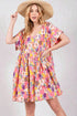 Woman wearing a colorful floral dress and straw hat on a plain background