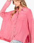 A woman wearing a pink textured button-up shirt with two chest pockets and light-wash distressed jeans, photographed against a plain light background.
