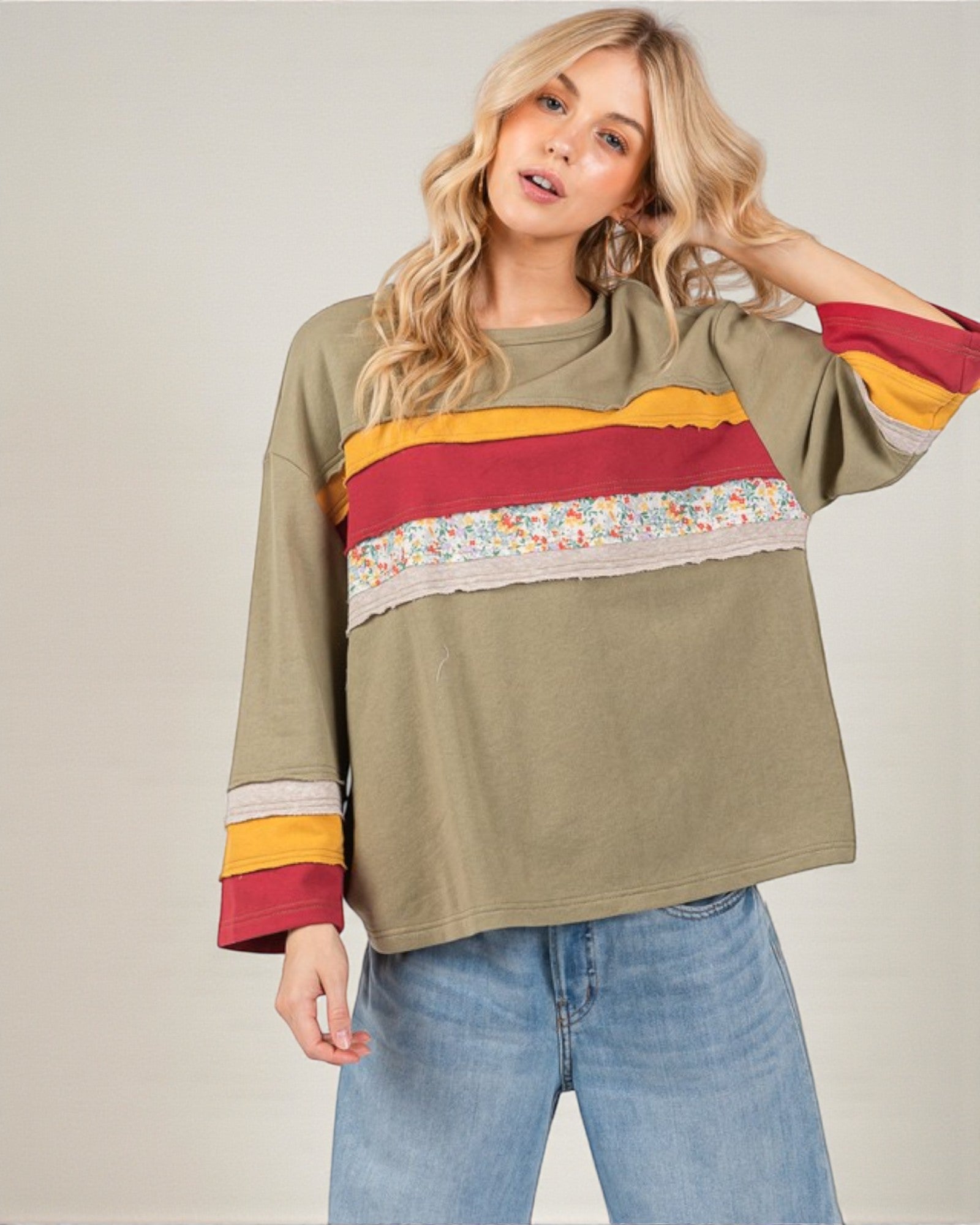 Woman wearing a colorful striped sweater with floral pattern on a plain background