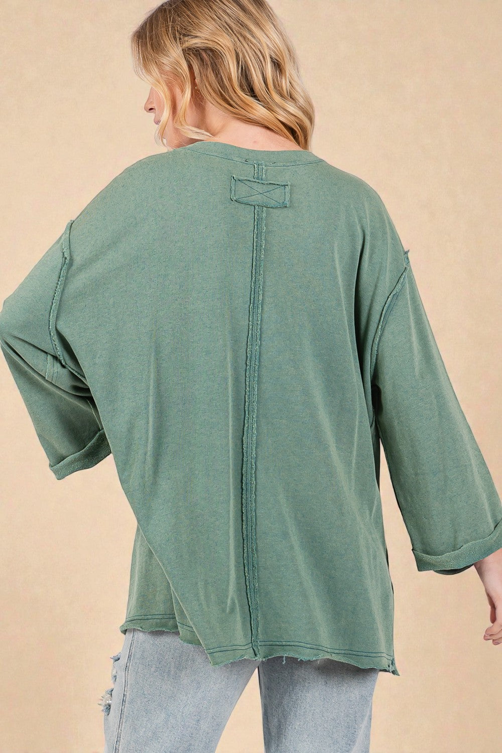 Green oversized shirt worn by a person on a beige background