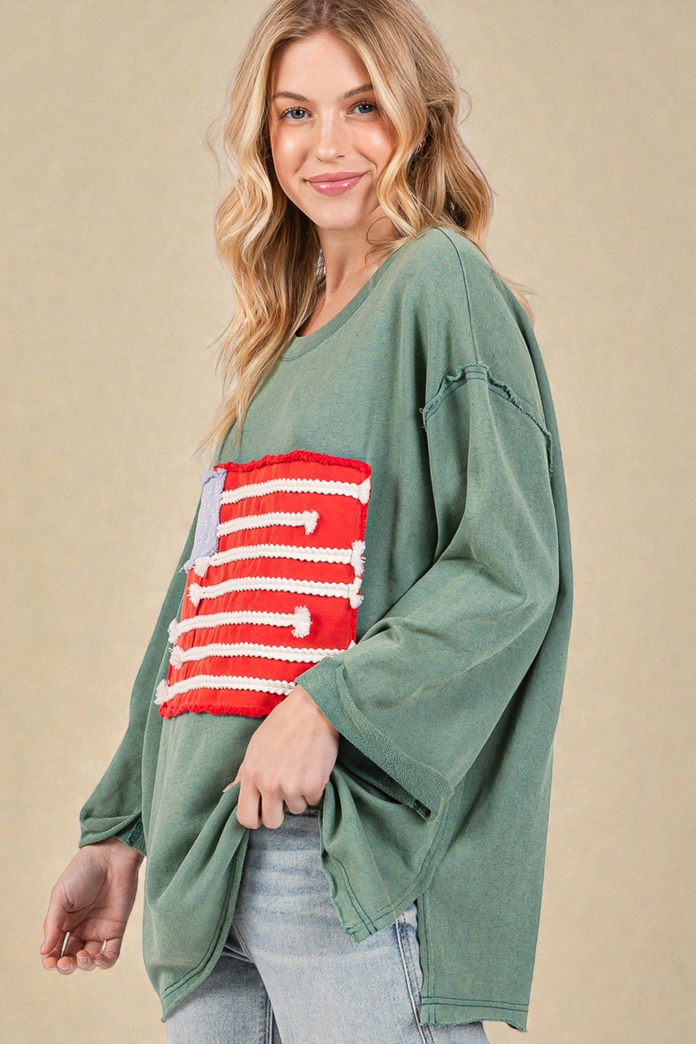 Woman wearing a green long-sleeve top with a red and white pattern on a beige background