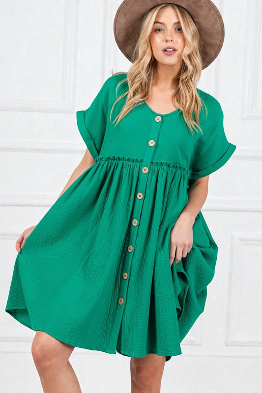 Woman wearing a green dress with brown buttons against a white background