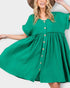 A woman wearing a bright green short-sleeve dress with a button-down front and gathered waist, posed against a light gray studio background.